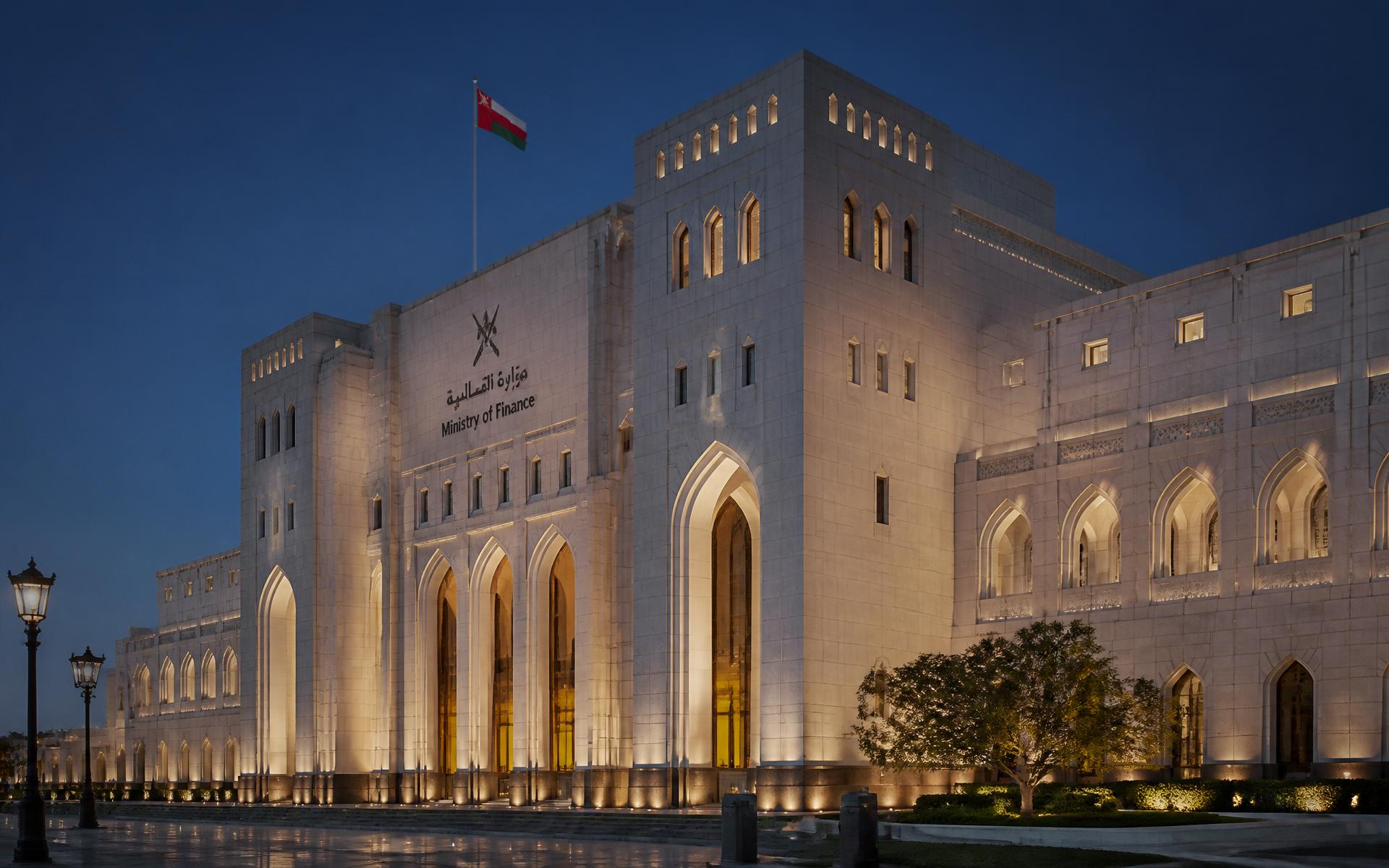 The Ministry of Finance building in Muscat at blue hour, warm arches lit against a deep navy sky